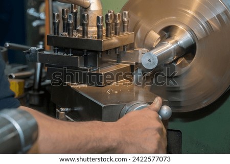 The machine operator working the  lathe machine. Shop floor operation with turning machine.