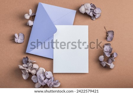 Lilac envelope on a brownish background, blank form and hydrangea flowers. Warm earthy tones.Greeting card, invitation.