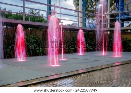 Jet of water from a splashing fountain, colorful lighting. Long exposure photo