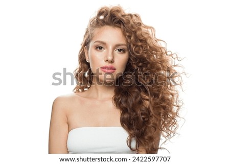 Gorgeous redhead female model with long frizzy ginger hair and clean soft fresh skin posing on white background. Studio fashion beauty portrait of young woman