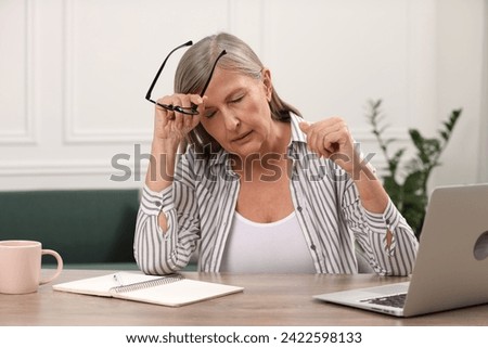 Menopause. Woman suffering from headache at wooden table indoors Royalty-Free Stock Photo #2422598133