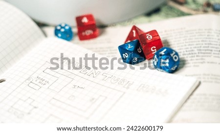 Role playing tabletop game and board game hobby concept. Blue dice D20 place on adventure story TTRPG book and character sheets. Creation with fantasy narrative at home.