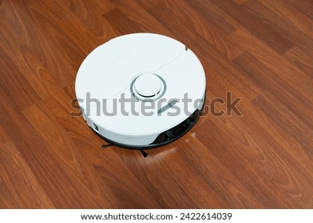 robot vacuum cleaner in modern smart home, robotic vacuum cleaner on wooden or laminate or parquet floor, cleaning dust on tile floors. Modern smart cleaning technology housekeeping. Royalty-Free Stock Photo #2422614039