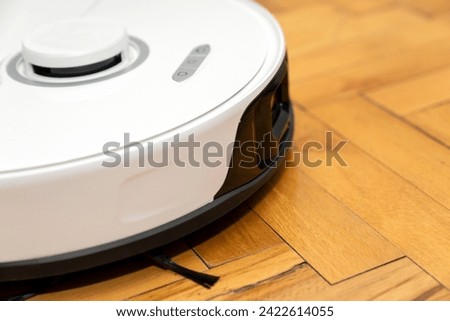 robot vacuum cleaner in modern smart home, robotic vacuum cleaner on wooden or laminate or parquet floor, cleaning dust on tile floors. Modern smart cleaning technology housekeeping. Royalty-Free Stock Photo #2422614055