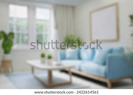 Blurred view of modern living room with sofa and soft bench. room interior with  couch, armchair and coffee table or shelving units. stylish living room. comfortable workplace near big window. Royalty-Free Stock Photo #2422614561