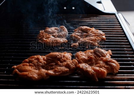 cooking a chicken in the grill with fire and is smoking
