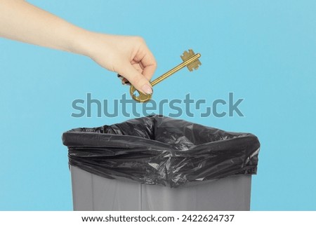 throw the door key into the trash, key in hand in front of trash can Royalty-Free Stock Photo #2422624737