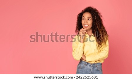 Delighted black woman gracefully touching her chin, gazing aside with smile space for text or graphics on charming pink background, panorama, place for promotion