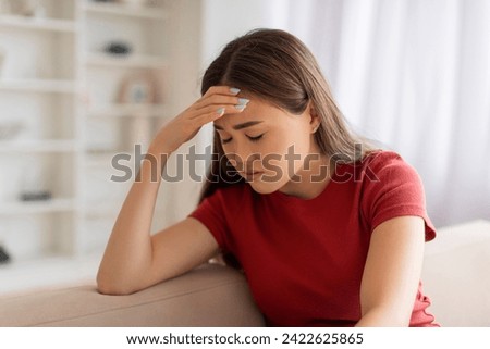 Portrait of stressed young asian woman with hand on her forehead sitting on couch at home, upset female showing signs of severe headache or emotional stress, dealing with personal issues Royalty-Free Stock Photo #2422625865
