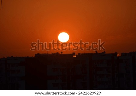 Sunrise orange coloured sky Sun clouds. Buildings silhouette photography black Crane machinary. Construction site foreground. scenic beauty. morning dawn winter season February month.