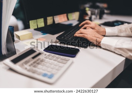 Elderly Caucasian male professional typing on a keyboard in a modern office setting, showcasing active employment and technology use in later life, with focus on hands and office tools Royalty-Free Stock Photo #2422630127