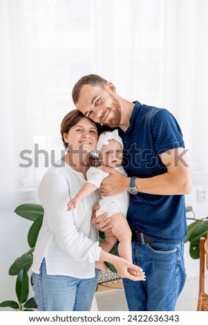 happy family mom, dad and little baby daughter hug and kiss, a young family at home with a newborn baby.
