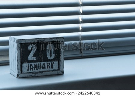 Morning January 20 on wooden calendar standing on window with blinds