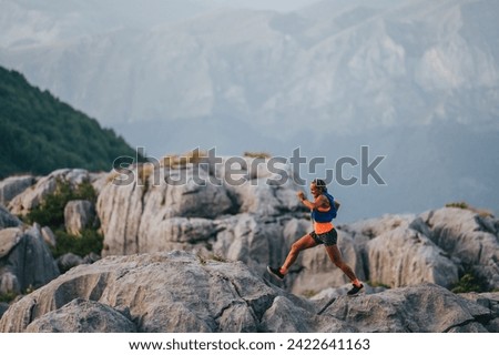 A female skyrunner is running and training on rocky mountain top. An extreme sportswoman is jogging, trail running and mountaineering in wild nature. A sportswoman is practicing for ultramarathon. Royalty-Free Stock Photo #2422641163