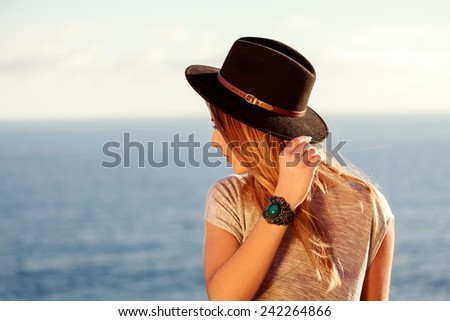 Young model with a hat with the sea in the background  