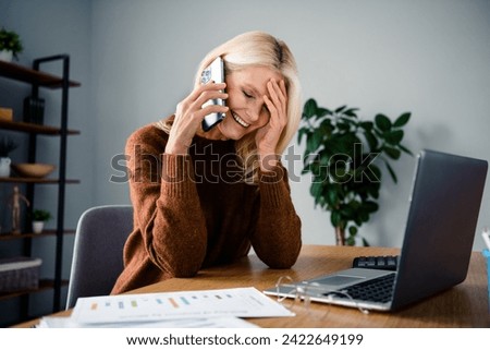 Photo of good mood laughing blonde hair pensioner woman touch forehead laughing during pause phone call in office modern interior indoors