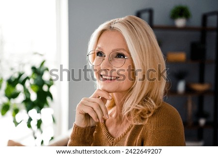 Photo of minded adorable cheerful lady hand touch chin dream comfortable apartment indoors