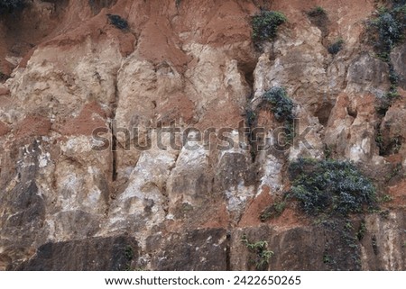 Cliff that formed because of erosion and weathering. Weathering happens when natural events, like wind or rain, break up pieces of rock. The picture is taken from a distance in zoom-in.