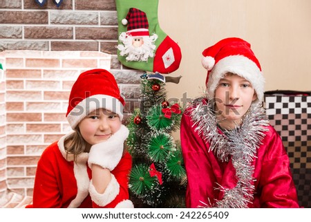 Brother and sister dressed costume Santa Claus by fireplace. Christmas and New Year