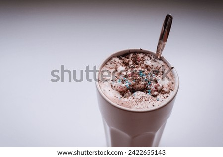 A big cup of hot chocolate with whipped cream and sprinkles and chocolate flakes. Cozy evening at home with warm drink. Pastel colors and cute mug.