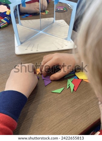Build a child creativity with educational activity. Hands of a small child using colorful shapes puzzles in front of angel mirrors. Kindergarten-age learning tools. Bright learning system
