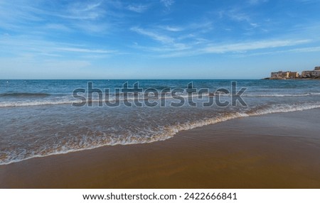 Sandy beach, colorful sky and sea waves. Fine golden sand beach of the Mediterranean Sea. Coast of the Costa Blanca, Torrevieja,  Alicante, Spain