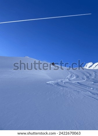 Heli-skiing and ski touring on a cloudless day with fresh powder Royalty-Free Stock Photo #2422670063