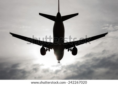 aircraft flying over a sky with clouds backlit