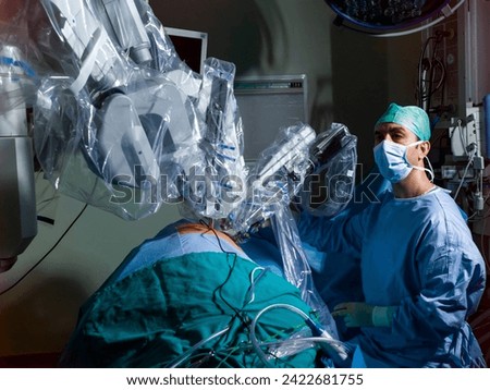 surgeon performing robotic surgery with robotic device. Medical operation involving robot. Operating room, medical surgical robot, cancerous tumor removal surgery. Minimally invasive robotic surgery.