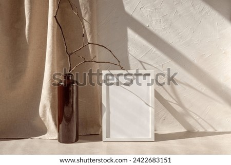 Empty picture frame mockup, vase with tree branch on beige table, neutral linen curtain and textured wall background with natural aesthetic sunlight shadows, lifestyle.
