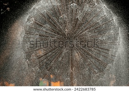 It's summer, it's hot in the city, a fountain is turned on, a beautiful fountain in the form of a large dandelion in the park, an abstract picture with water.