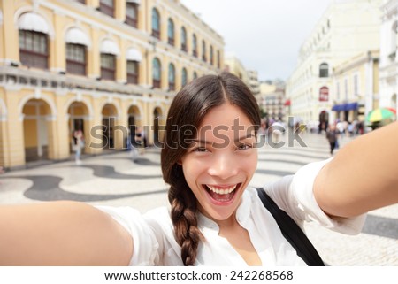 Selfie woman taking fun selfportrait in Macau, China in Senado Square or Senate Square. Asian girl tourist using smart phone camera to take photo while traveling in Macau. Travel and tourism concept.