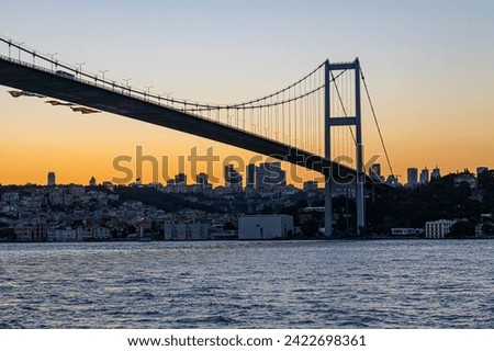 Istanbul, Turkey - July 15 2022: Bosphorus bridge at sunset and the Istanbul's sicyscape on background. View from a tourist boat.