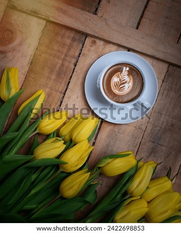 Coffee mug with yellow tulip flowers and notes good morning on blue rustic table from above, breakfast on Mothers or Women day