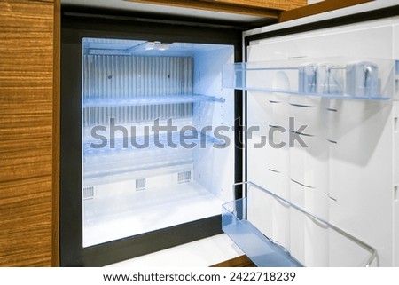 Black mini small fridge refrigerator under the frame wooden counter in hotel resort bedroom, or hospital patient room or home.	