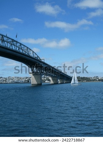 A monohull sailboat cruising underneath the harbour bridge. Royalty-Free Stock Photo #2422718867