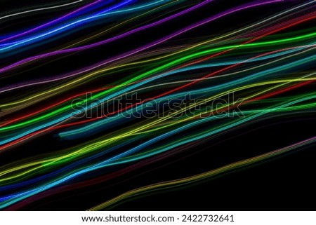 Multicolored abstract lines of light trails against black background. Long exposure photography

