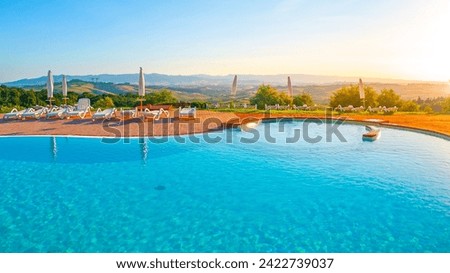 Blue swimming pool and beautiful hilly panoramic landscape at sunset time