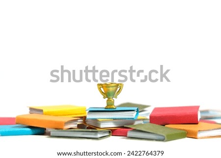 A golden trophy stand above piles of books. Isolated on a white background. Image photo
