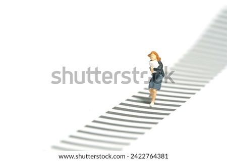 Miniature tiny people toy photography. Front view of a girl pupil student running on zebra crossing crosswalk. Isolated on a white background. Image photo