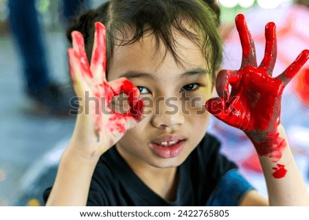 Young messy hands girl playing with painting color making ok sign in art school