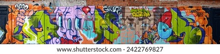 The old wall decorated with paint stains in the style of street art culture. Colorful background of full graffiti painting artwork with bright aerosol outlines on wall. Colored background texture Royalty-Free Stock Photo #2422769827