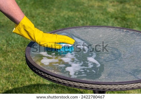 Cleaning patio furniture by hand with brush. Spring cleaning, household chores and home improvement concept.