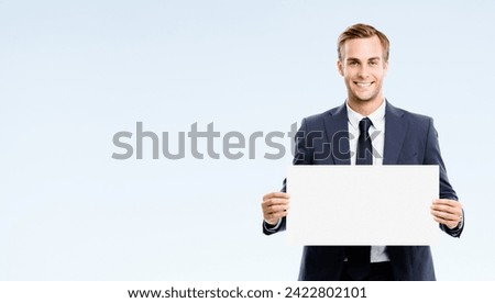 Happy business man wear suit, necktie show advertising mockup sign board, empty banner copy space for ad text or slogan, isolated gray grey background. Businessman hold blank white paper at studio
