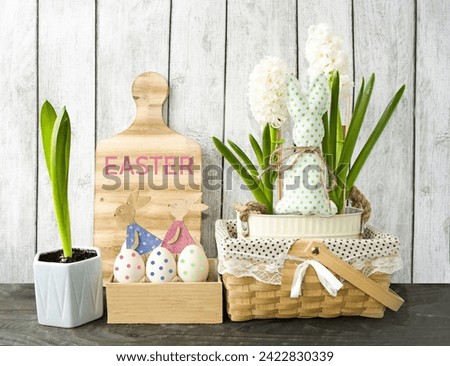 Decorative Easter composition on a wooden background, spring flowers hyacinths and cute wooden bunnies in a box with Easter eggs. foreground. Easter holiday concept, festive decor.