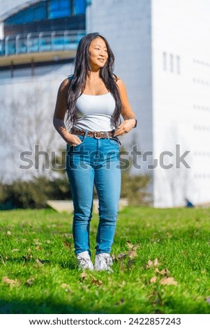 Vertical photo of a chinese cool student standing on the grass of the campus