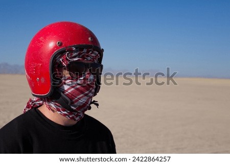 Portrait of man in red helmet and keffiyeh against the backdrop of the Arabian desert and clear sky during safari in Egypt
