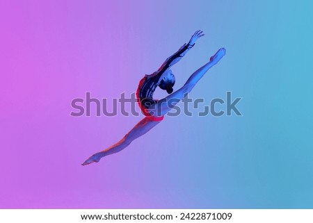Jumping in a twine. Rhythmic gymnast in motion, teen girl performing against gradient studio background in neon light. Concept of sport, beauty and grace, competition, art, youth, hobby