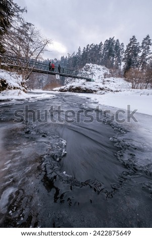 Half-frozen Hornad river with rapids in winter at sunset Slovak Paradise. An iron bridge over a frozen river. Discovering the beauty of the winter landscape. Royalty-Free Stock Photo #2422875649