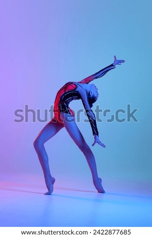 Talented, artistic teen girl in bright costume, rhythmic gymnast dancing against gradient studio background in neon light. Concept of sport, beauty and grace, competition, art, youth, hobby Royalty-Free Stock Photo #2422877685